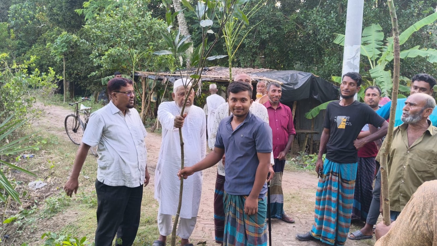 Villagers gathered on the road holding a sapling before planting