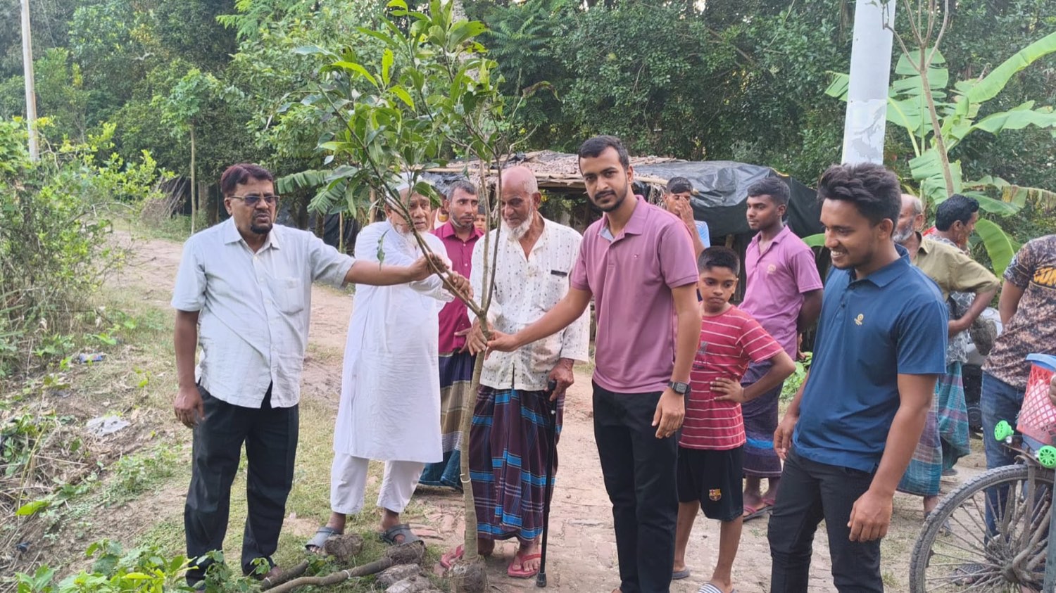 Volunteers and village elders gathered around a sapling at the roadside in Berbari