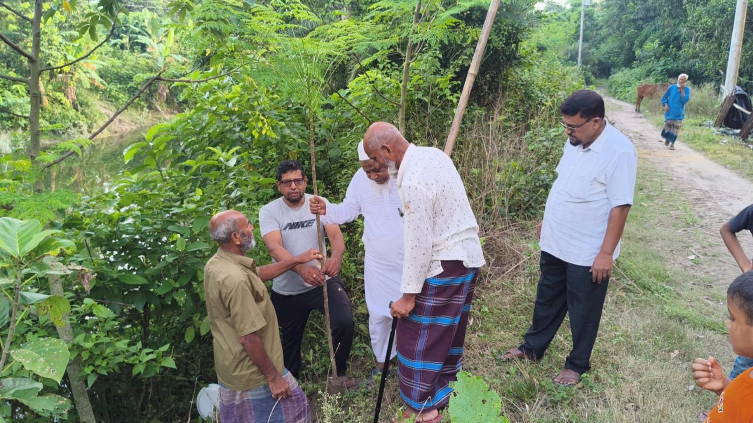 Volunteers and elders steadying a newly planted sapling