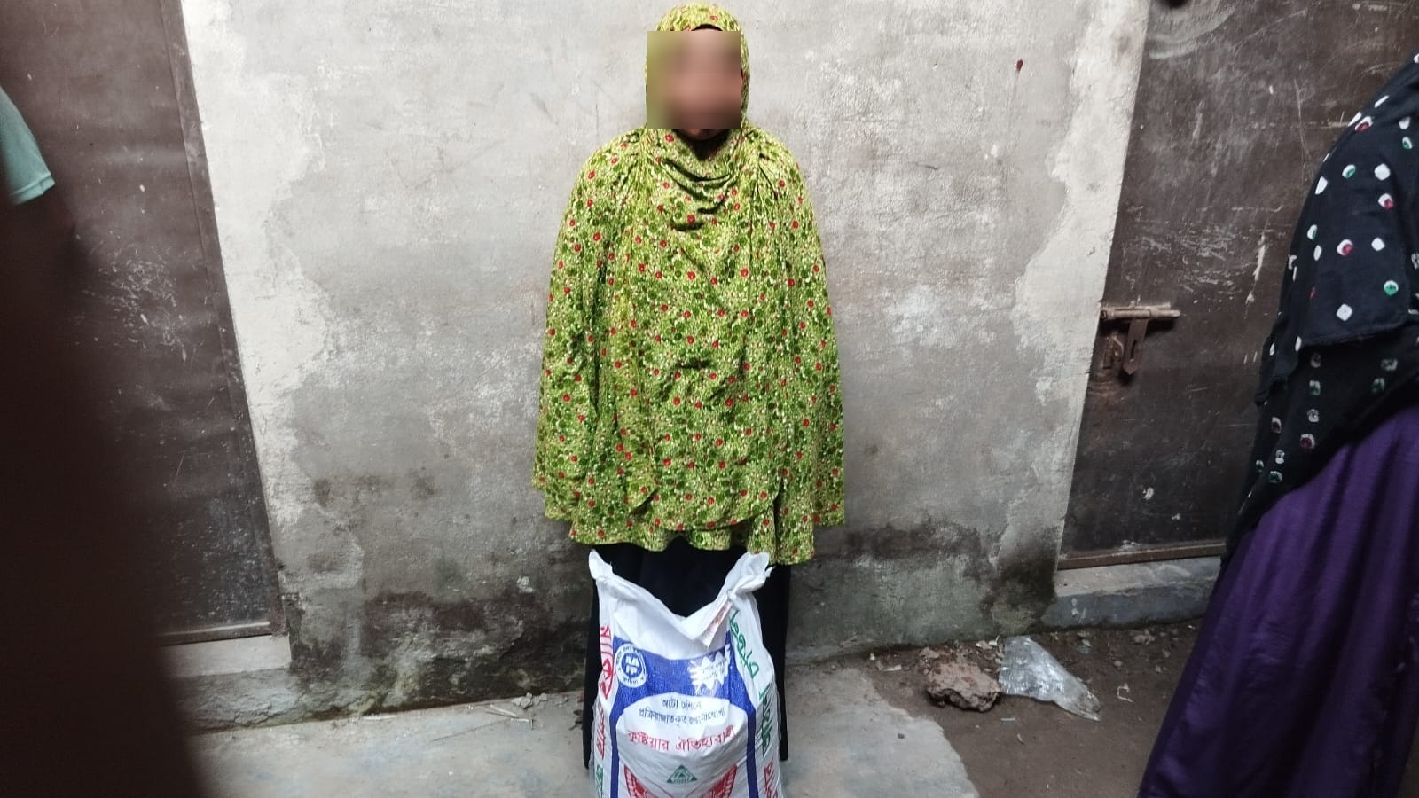 Woman in a green headscarf with a sack of rice from the distribution