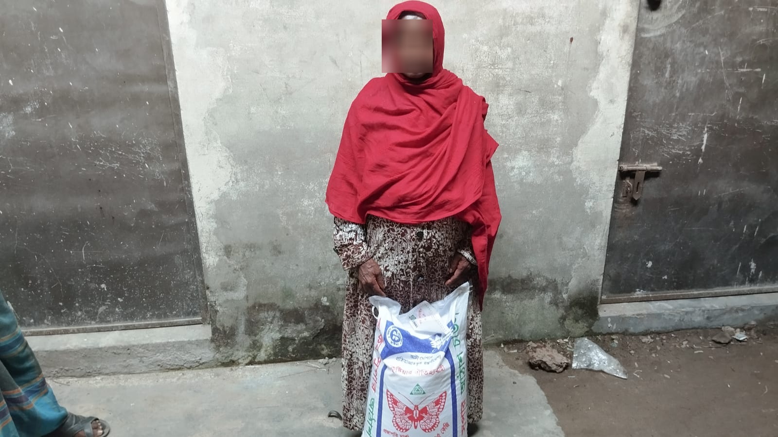Woman in a red headscarf holding a sack of rice