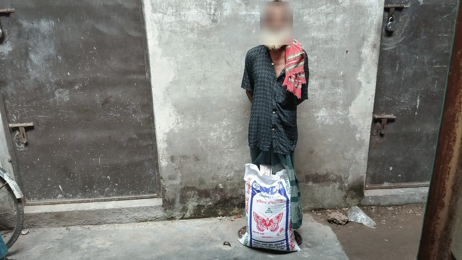 Elderly man standing behind a sack of rice from the distribution