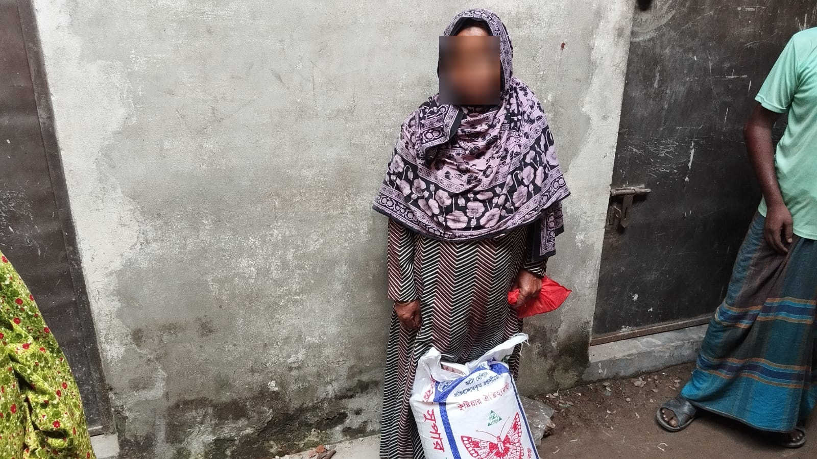 Woman in a floral headscarf with a sack of rice