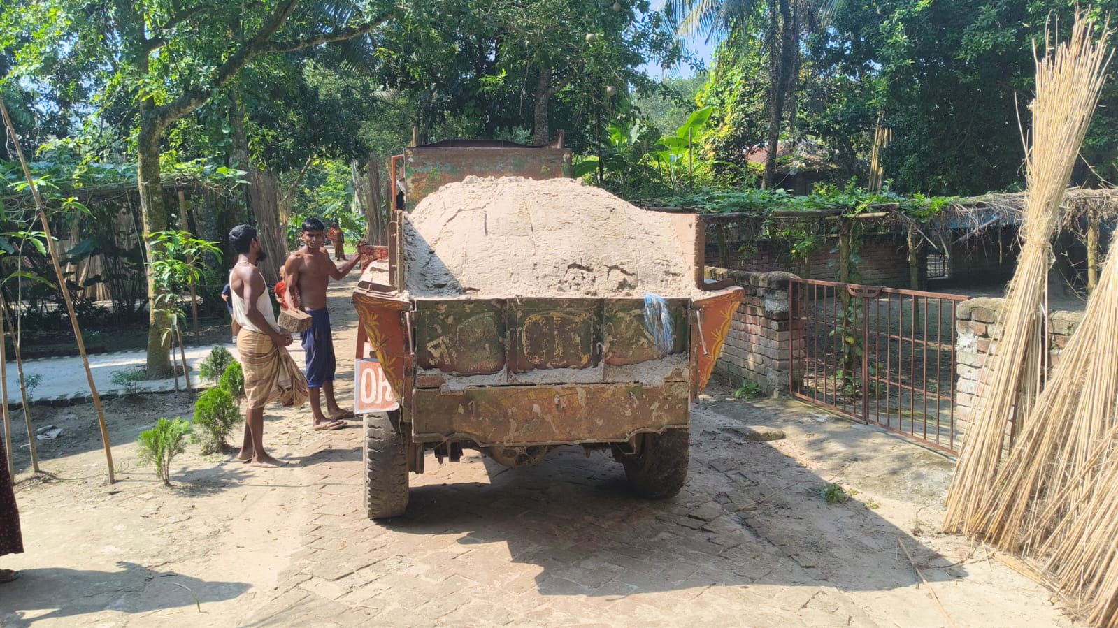 A truck loaded with sand arriving on the village road