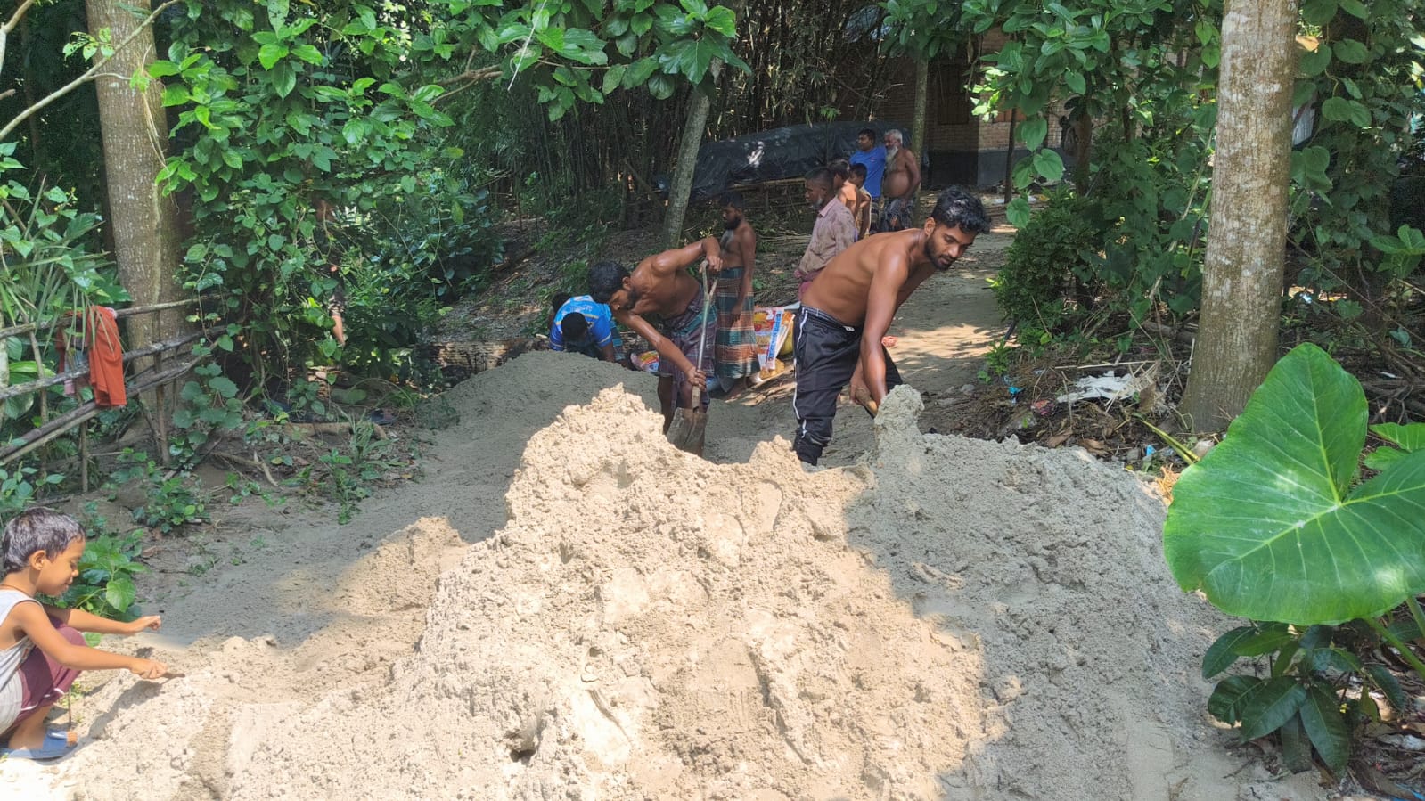 Volunteers spreading sand along the village path